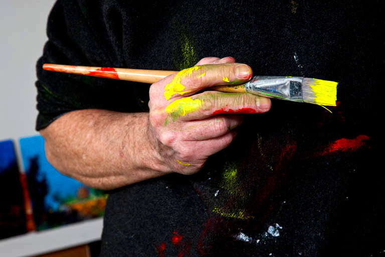 Artist's paint marked hand poised for the next stroke of genius